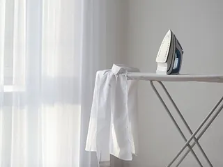 Mesa de planchar con camisa blanca sobre ella